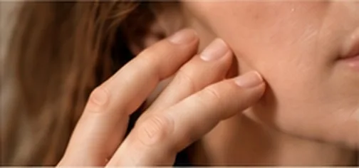 Manos sobre el cuello y la cara, en un gesto de tapping
